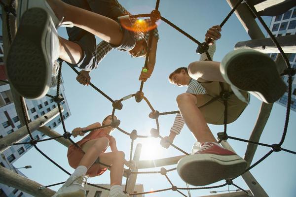 Children sitting on a climbing apparatus.